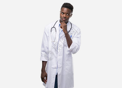 穿着医生大衣的年轻非洲男子面对着严肃的面孔思考问题图片