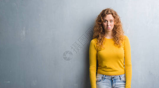 灰墙上的红发女青年沮丧并担心痛苦愤怒和恐惧图片