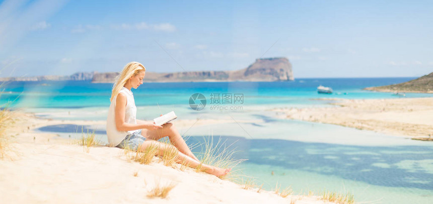 享受阳光自由和好书的轻松的女人在希腊Balos的美丽沙滩年轻女士阅读图片