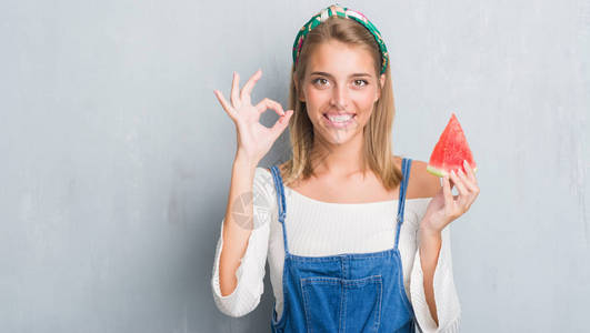 美丽的年轻美女在黑灰墙边吃西瓜吃着水瓜用手指做好标记图片
