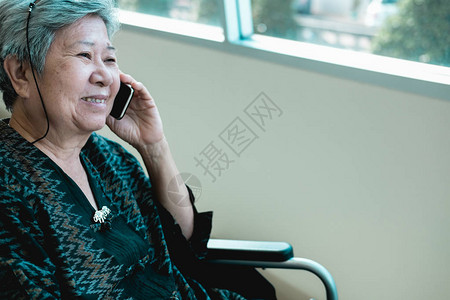 坐在轮椅上的老妇人用手机说话老年女在智能手机上发言前图片