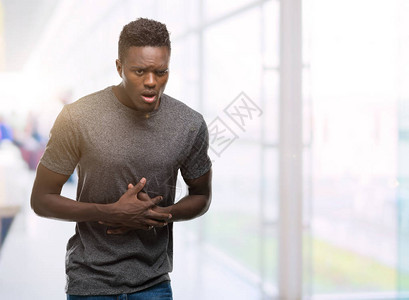 身着灰色T恤的年轻非洲美国人因为消化不良痛苦病痛不适而胃疼图片