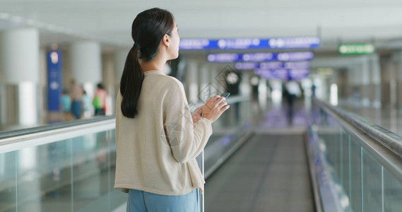 女人在机场用手机查看航班号图片