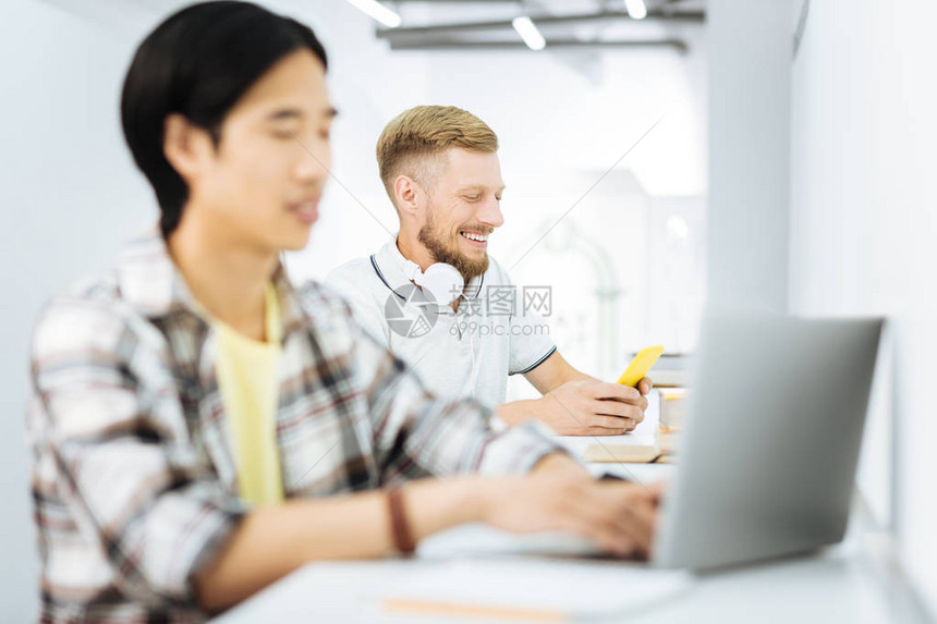 两个年轻人坐在简洁的联合办公空间的办公桌前图片
