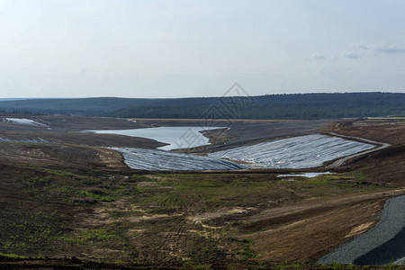 底部和岸上防水的地貌景观中正在建造的工业尾矿池背景图片