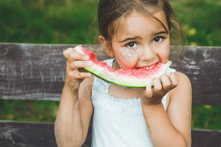 孩子在花园里吃西瓜孩子们在户外吃水果儿童健康零食在花园里玩耍的小女孩图片