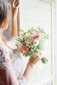 新娘在窗前拿着一束在照相馆背景图片