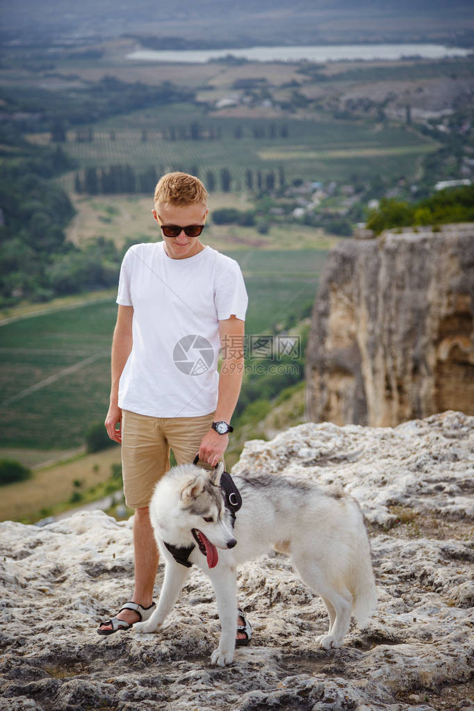带着西伯利亚哈士奇犬的徒步旅行者在山上看美丽的景色图片