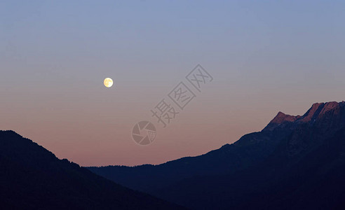 月亮在太阳光照耀的山岳背景下闪烁图片