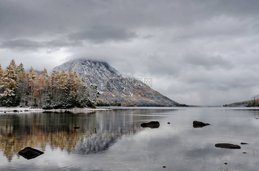 秋天在俄罗斯西伯利亚布里亚提的镜形湖上下着雪的Froliha山湖图片