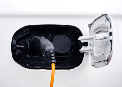 电动汽车充电器黄黑电缆在停车场插入现代生态图片