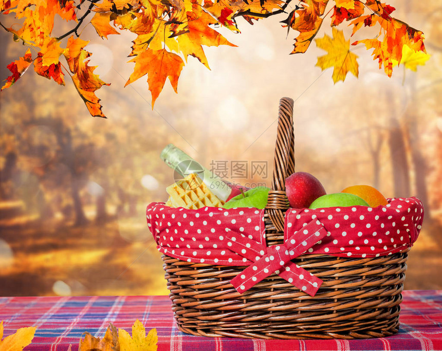 带秋叶和野餐篮的木桌图片