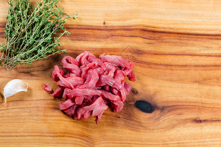 切菜板上的生牛肉条和香草图片