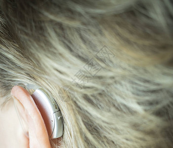 耳中佩戴现代技术数字助听器的聋哑女士背景图片