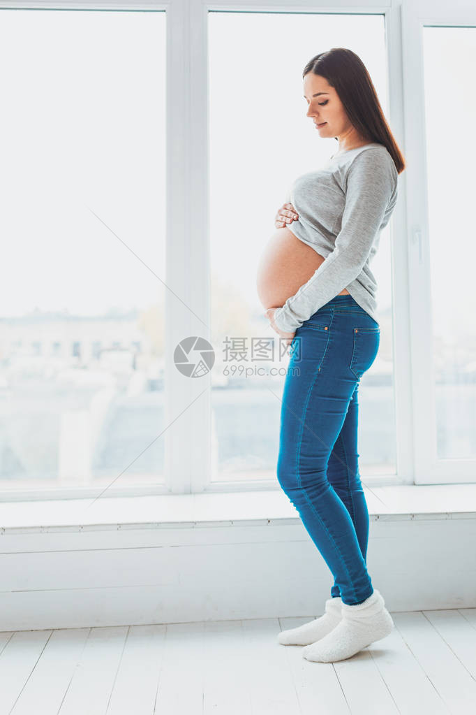 期望着年轻女在轻的客厅里抱着婴儿摇欲坠的姿图片