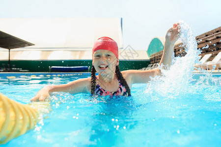 快乐微笑美丽少女在游泳池的画像蓝色水域的小孩游泳池休闲游泳夏季健康图片