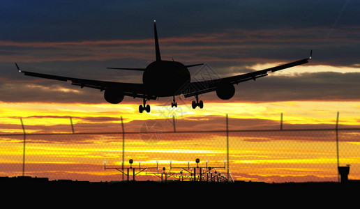 在日落天空降落时的休眠飞机喷气机抵达机场背景图片