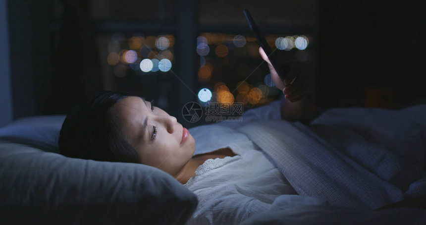 妇女使用手机晚上躺图片