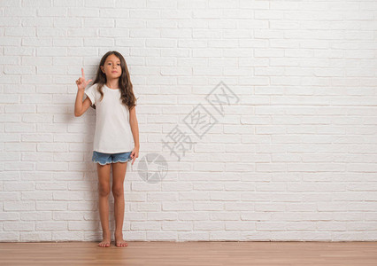 年轻的西班牙小孩在白砖墙上挥舞着图片