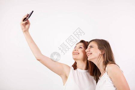 两名年轻美女在摄影棚的白墙上拍着自拍图片