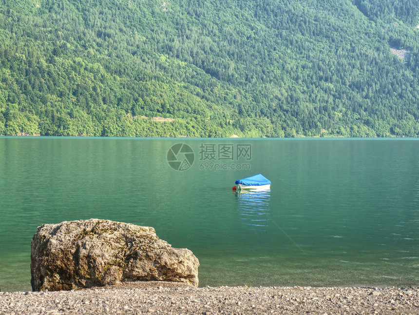 在阿尔卑斯湖绿色蓝水位的小船山湖的白色石质海岸森林山图片