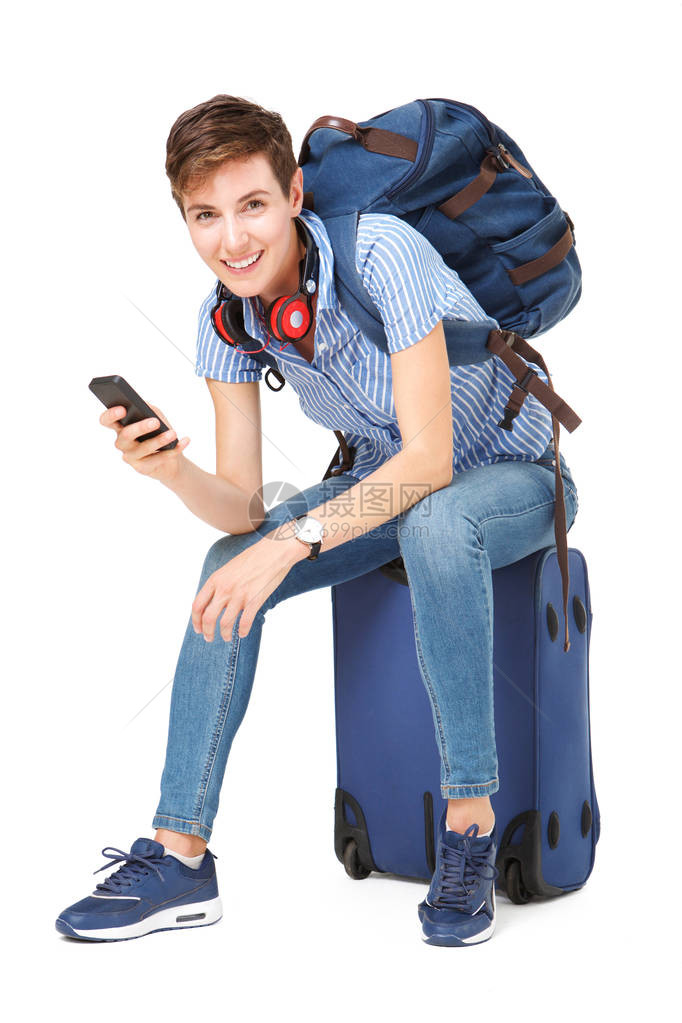 坐在手提箱上手持移动电话的年轻女图片