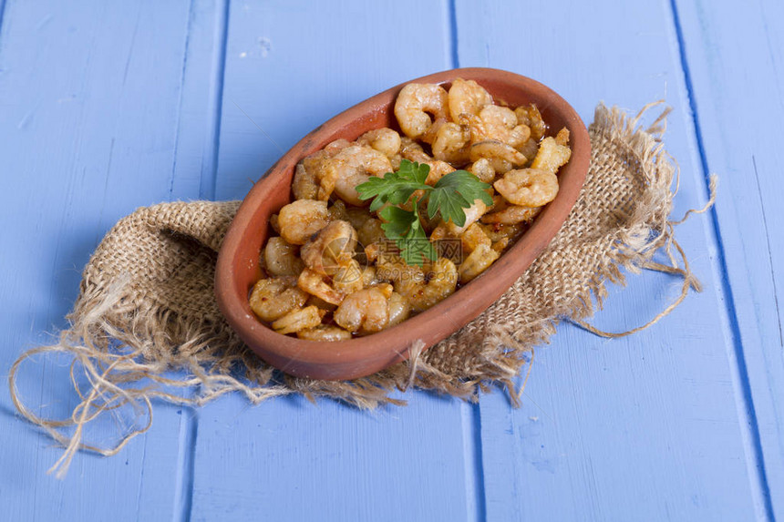 美味的小红虾在调味黄油和香料中煮沸虾在传统的希腊陶器炖菜中供应顶视图蓝色乡村背景最常见的食物过敏原图片