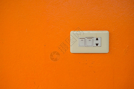 橙色墙上的电插头和开关图片