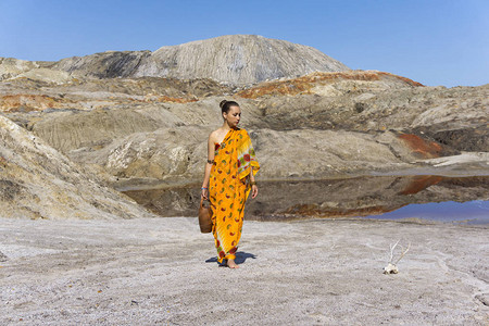 身穿沙里加壶子的年轻女子从一个干旱无生命地区的池塘里冒出来仔细地看图片