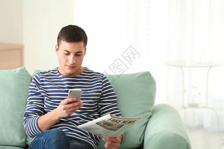 有手机和报纸的帅哥在家沙发图片
