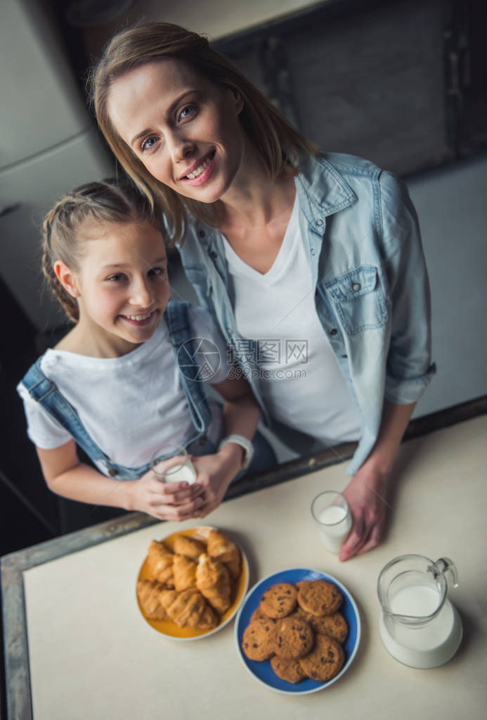 身着散衣的妈和女儿在家中厨房吃饼干喝牛奶时图片