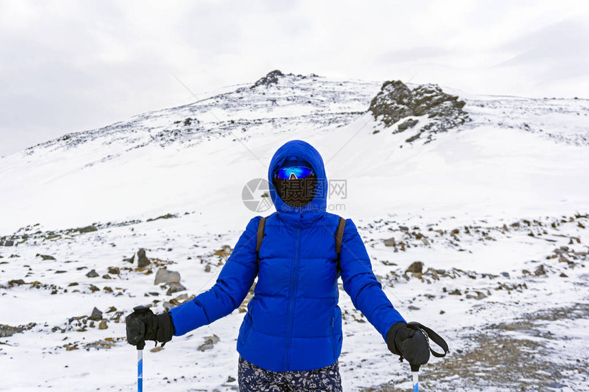 冬季山上穿着温暖衣服防风面具和防风眼镜的女孩登图片