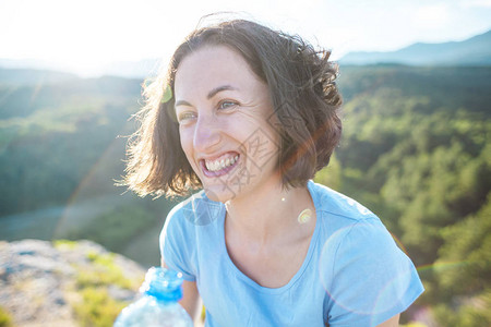 一个女人的肖像山上微笑的女孩日落时发色强风吹动旅行者的头图片