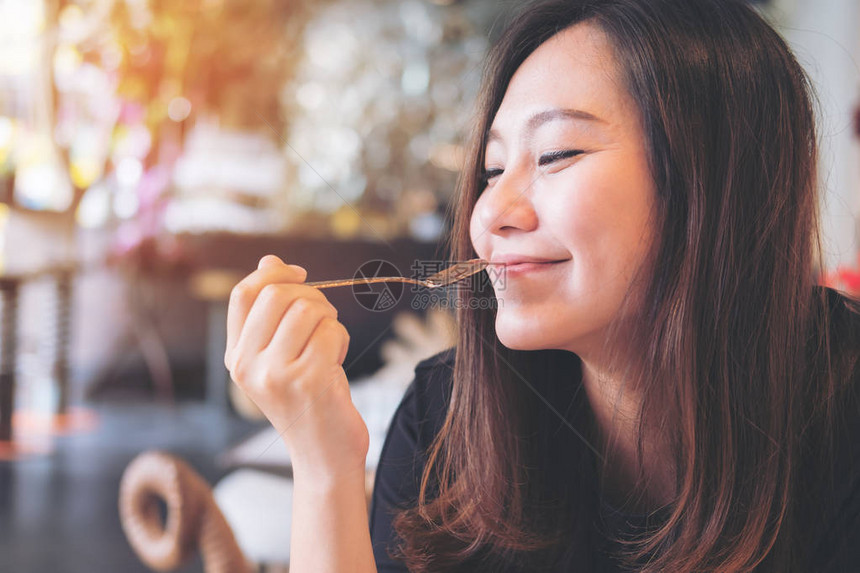 一位美丽的亚洲女在现代咖啡厅享受食物时图片