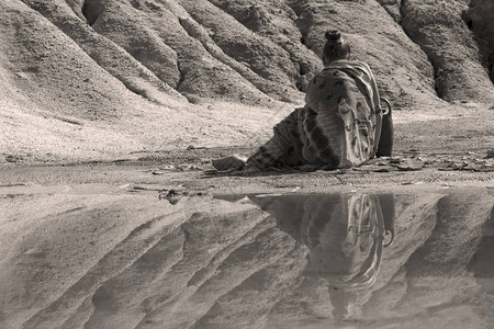 身着民族服装的年轻女子坐在荒漠山谷湖岸边图片