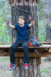 可爱年轻运动瘦弱和勇敢的男孩在冒险绳子公园图片