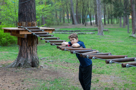 可爱年轻运动瘦弱和勇敢的男孩在冒险绳子公园图片