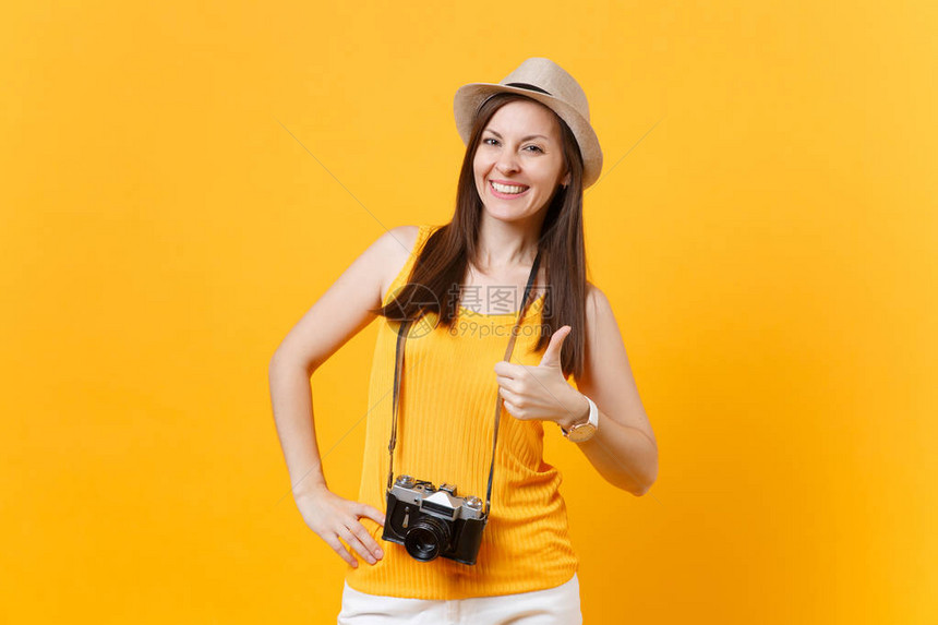 穿着夏季休闲服戴着复古老式照片相机的帽子的快乐旅行者旅游女在黄橙色背景下被隔离图片