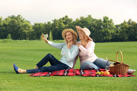成熟女在公园野餐时自拍背景图片