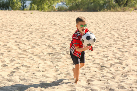 在沙滩上踢足球的小男孩图片