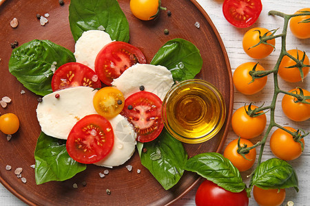 新鲜切樱桃西红柿奶油芝士和碗盘上含橄榄油的图片