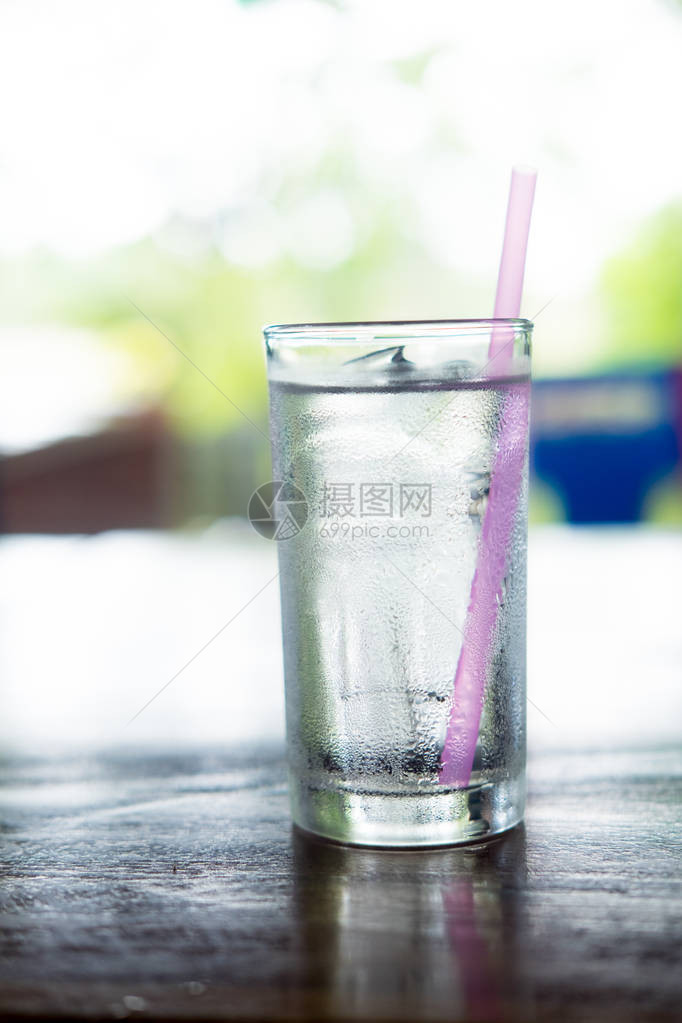 透明杯子用冷水倒在木制桌上的图片