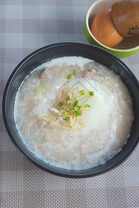 大米粥或煮猪蛋的粥切姜和蔬菜图片