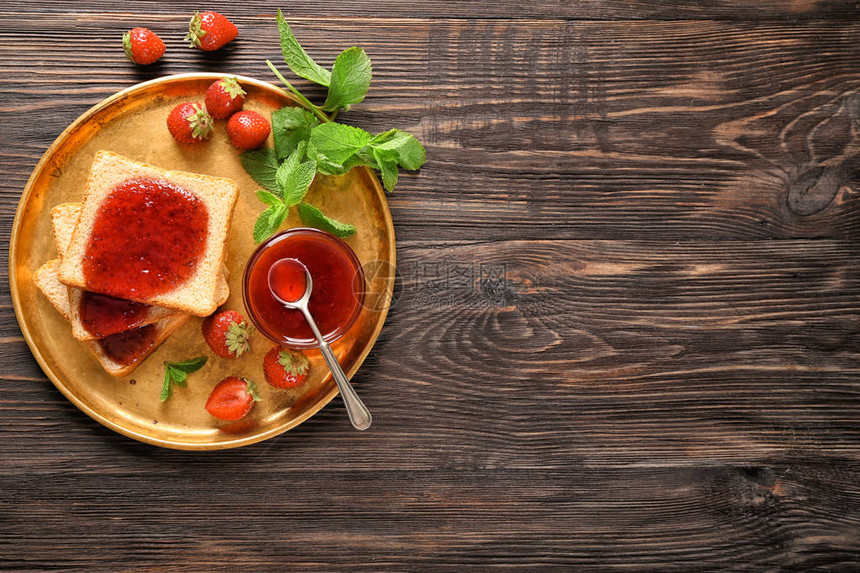 木桌上放着面包片和美味草莓酱的盘子图片