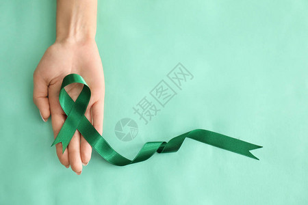 持有彩色背景绿丝带的妇女肾上图片