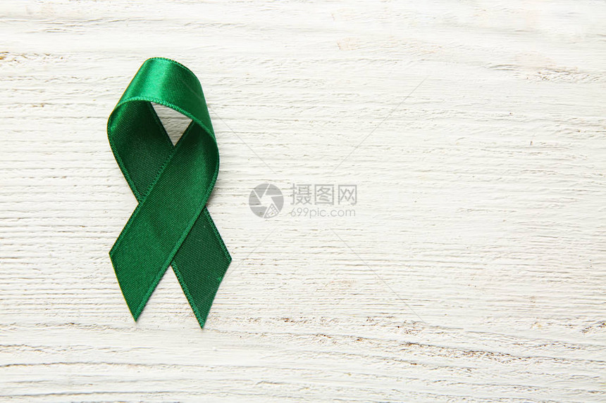 木制背景上的绿丝带癌症概念图片