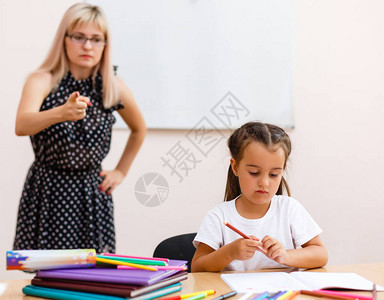 一个严格的老师和一个小学生小女孩在教室的书图片