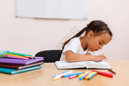 坐在书桌上看书的年轻女孩孤立图片