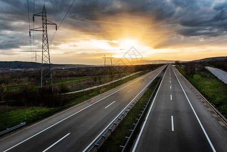美丽的寂静乡村高速公路和日落时的电力线图片