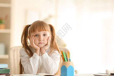 可爱的小女学生坐在桌边还有背景图片
